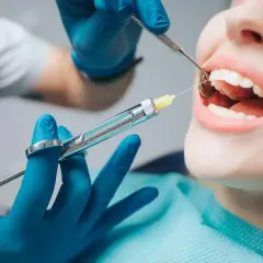 Dentysta podaje znieczulenie komputerowe pacjentowi, który ma otwarte usta.