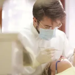 Dentysta w masce i rękawiczkach wykonuje zabieg. Pacjentka leży na fotelu. Pytanie: ile L4 po wyrwaniu ósemki?
