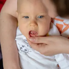 Malutki, niebieskooki bobas z otwartymi ustami, gdzie widać, jak wyglada przebijajacy sie zabek.