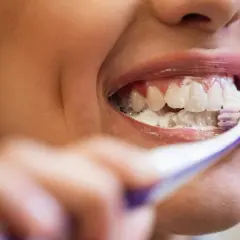 Uśmiechnięta osoba myje zęby, używając szczoteczki i piany. To dowód, że znalazła najlepszą pastę do zębów dla siebie.