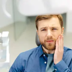 Mężczyzna z bólem zęba po zatruciu, szuka pomocy.