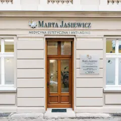 Elegancka fasada kliniki medycyny estetycznej "Marta Jasiewicz" z drewnianymi drzwiami i oknami.