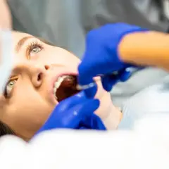 Pacjentka z otwartymi ustami, dentysta podaje znieczulenie. Ciekawe, ile trzyma znieczulenie po wyrwaniu 8.