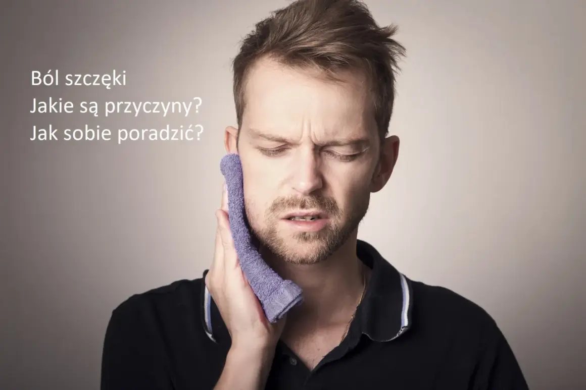Mężczyzna z wyrazem bólu na twarzy przykłada fioletową ściereczkę do policzka, cierpiąc na ból szczęki.