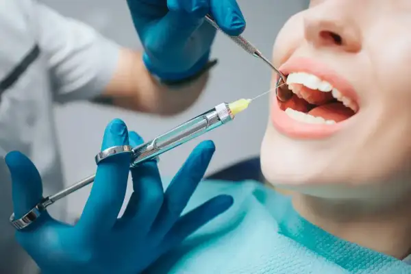 Dentysta podaje znieczulenie. Zastanawiasz się, ile kosztuje znieczulenie u dentysty? To zależy od zabiegu i rodzaju znieczulenia.